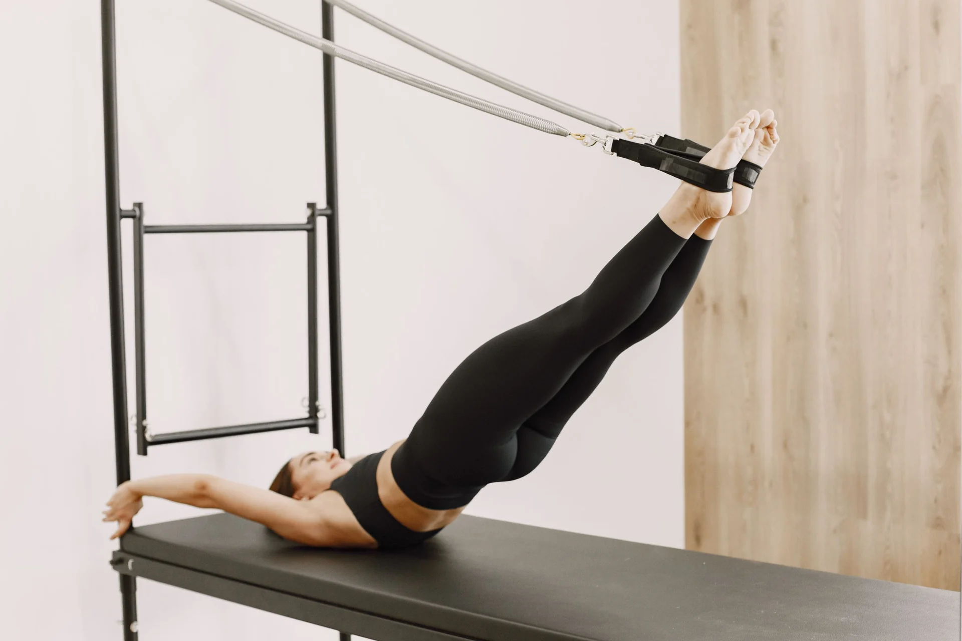 Aluna praticando Pilates em equipamento reformer, em um estúdio claro e silencioso